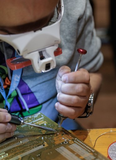 Un homme répare un objet électronique avec un fer à souder
